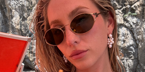 Alix Earle poses in Instagram picture wearing gold Miu Miu oval sunglasses with logo on temples. 