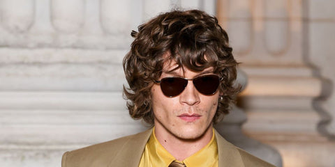 Heated Rivalry star Connor Storrie was seen wearing gold Saint Laurent Sun SL 831 Vesper 005 sunglasses with brown lenses at the Saint Laurent Menswear Fall/Winter 2026 fashion show during Paris Men's Fashion Week