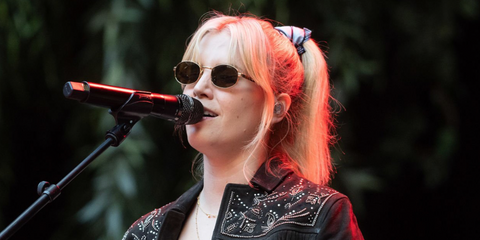 Hannah Reid, lead vocalist of London Grammar, was seen wearing gold Prada PR B53S 5AK09Z oval sunglasses with havana temple on stage at Principality Stadium in Cardiff, Wales, July 2025. Shop online now on Pretavoir
