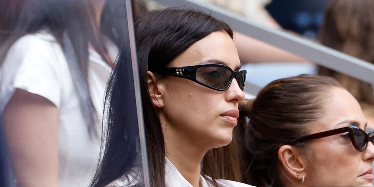 Irina Shayk wore black Miu Miu MU C06SU 16K80Q wraparound sunglasses at the US Open 2026.