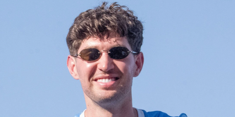 Footballer John Stones of Manchester City was seen wearing old gold Miu Miu MU A54S 26C09Z rimless oval sunglasses during an open top bus parade, May 2026.