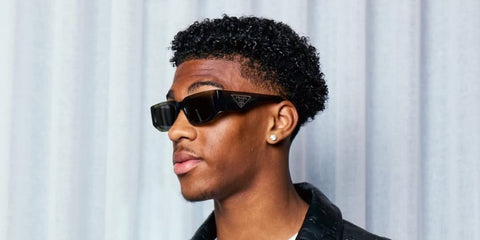 Footballer Josh Acheampong of Chelsea FC was seen wearing transparent grey Prada PR 09ZS 18S09T sunglasses in his Instagram post, May 2025.
