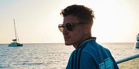 Argentine footballer Julian Alvarez of Atletico de Madrid was seen wearing pale gold Prada PR 65ZS ZVN20I sunglasses with purple brown lenses in a social media post.