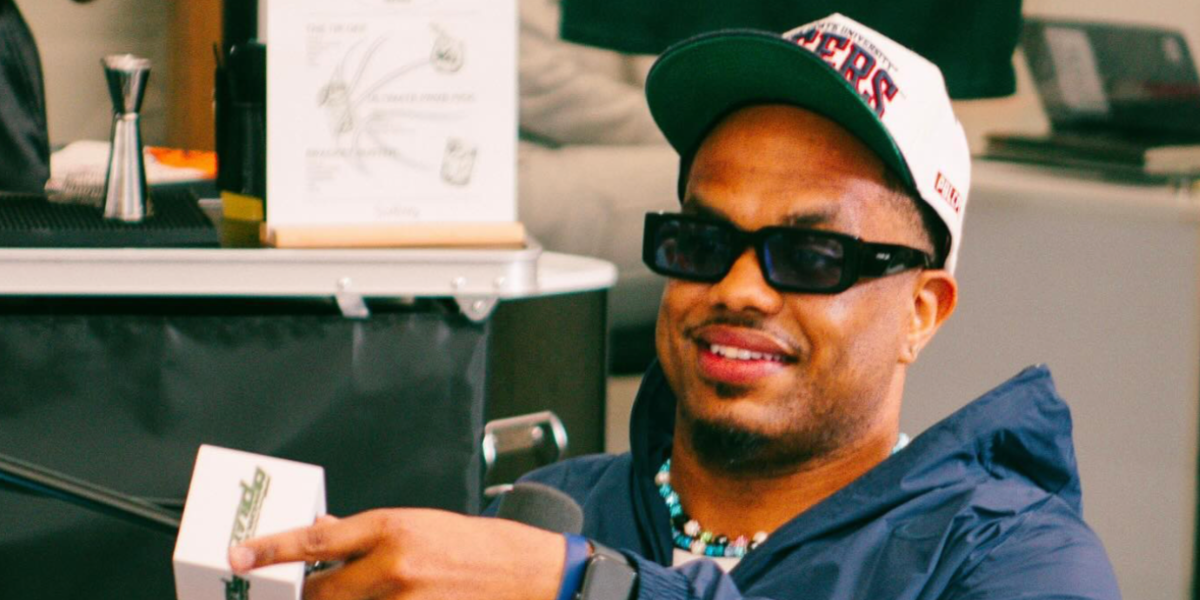 Comedian Lou Young III was seen wearing black Prada PR 06YS 16K10L sunglasses with light blue lenses in his Instagram post, April 2024.