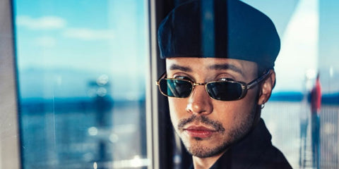 Colombian YouTuber Mario Andres Ruiz was seen wearing gold Prada PR B54S 5AK40K rectangular sunglasses with blue-green lenses in Las Vegas, shared through his Instagram post in November 2025.