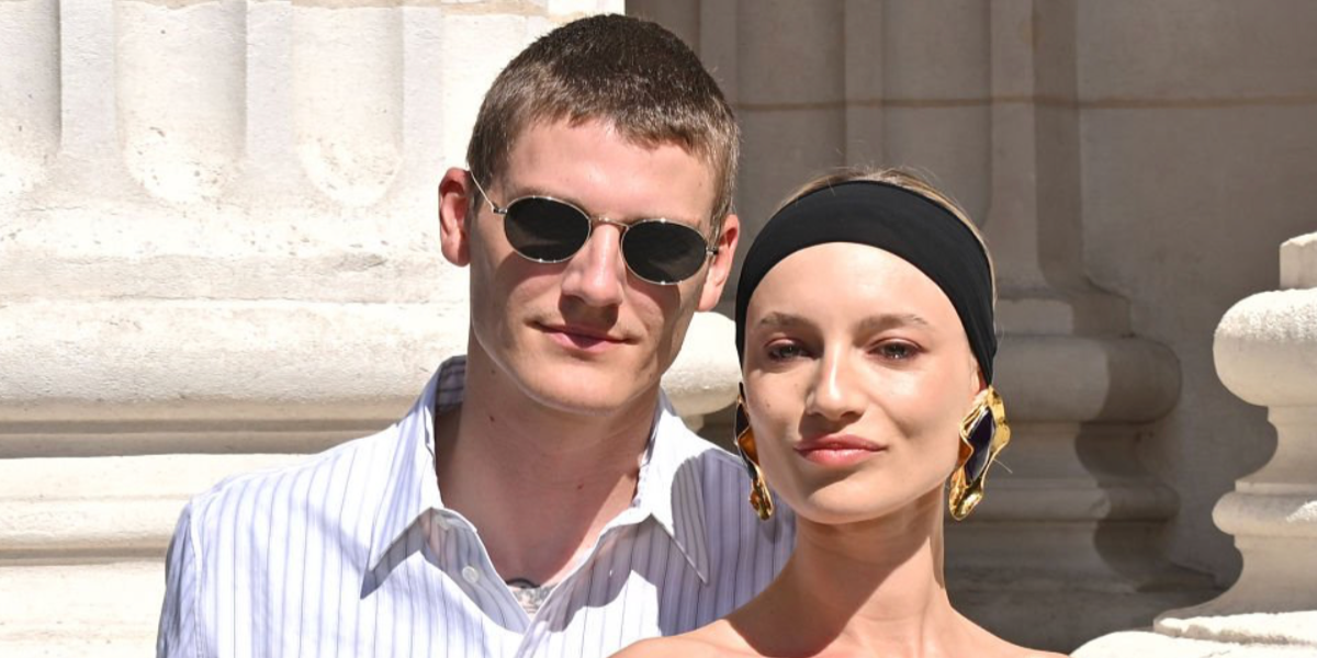 Model Mikkel Jensen, pictured alongside girlfriend Maya Stepper, was seen wearing silver Saint Laurent SL 799 002 round oval sunglasses at the Saint Laurent Menswear Spring/Summer 2026 fashion show during Milan Men's Fashion Week.