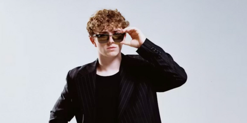Actor Walker Scobell was seen wearing black Ray-Ban Wayfarer Deluxe RB 3875 006/4E sunglasses with green lenses in an Inverse Magazine feature, December 2025.
